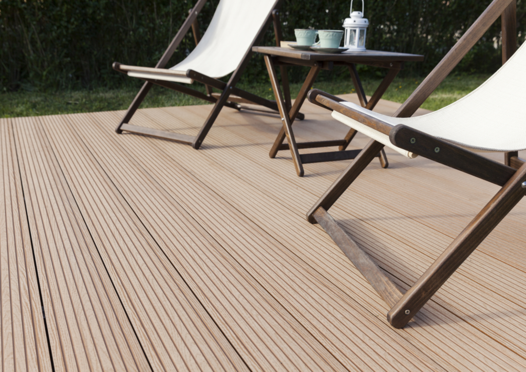 Terrasse en bois composite avec mobilier de détente, chaise longue blanche et table basse en bois, entourée de verdure