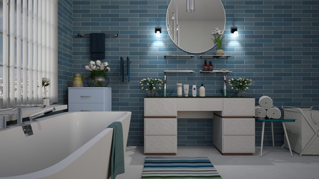 Salle de bain moderne avec carrelage bleu, double vasque en pierre, miroir rond éclairé, baignoire blanche et accessoires de